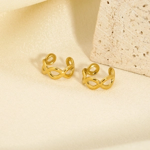 Detailed view of infinity-shaped gold ear cuffs on beige silk with stone background