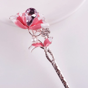 Detailed view of silver hair stick featuring pink enamel flower and purple pear gemstone