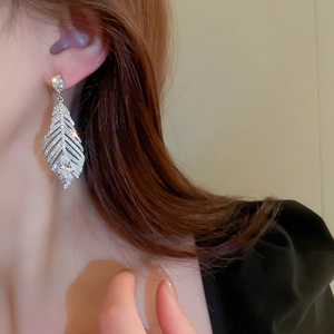 Primo piano di orecchini a piuma in argento con goccia di zircone indossati da modella