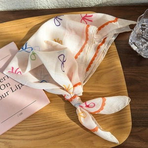 Detail of floral linen headscarf with colorful bow patterns and orange wavy edges