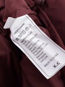 Detail view of the 100% polyester care label and washing instructions on a burgundy jacket