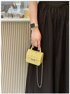 Close-up of yellow quilted jelly handbag with elegant metal chain strap for women