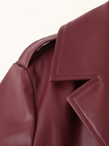 Détail des épaulettes et du col à revers sur une veste longue en cuir rouge foncé