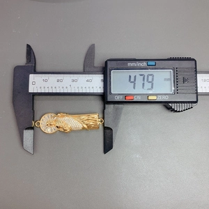 Close-up of golden Saint Jude pendant size measurement showing 47.9mm on a digital caliper