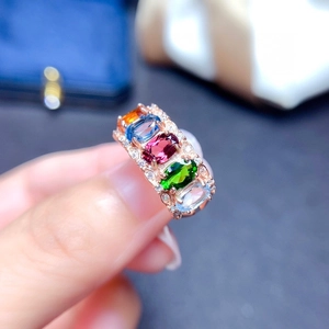 Close-up of rose gold ring featuring five oval colorful gemstones and small diamonds