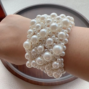Hand wearing multilayer white faux pearl stretch bracelet with elegant woven bead layers