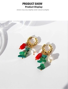 Detail of twisted gold hoop earrings with green natural stones and a white pearl drop