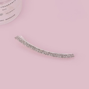 Elegant silver rhinestone bow hair clip on pink background with candle accent