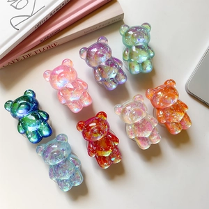 Set of 8 glitter resin bear phone grips in assorted aurora colors on a minimal desk