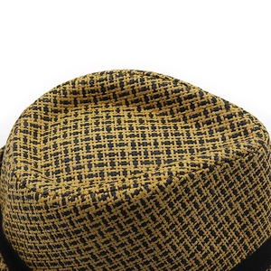 Detail of two-tone woven straw fedora hat featuring black ribbon and grid texture