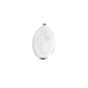 Macro detail of oval stainless steel pendant with fine silver floral engraving and top loop
