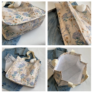 Detailweergave van bloemen canvas draagtas met stiksel en witte pluche bal hanger