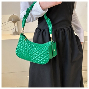 Detail of emerald green quilted shoulder bag with ruched strap and mini coin purse