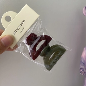 Detail of two solid jelly mini hair clips in burgundy and dark green colors on a card