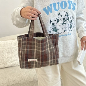 Detail shot of vintage plaid tote bag with woven brand label and textured fabric pattern