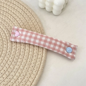 Close-up of pink checkered fabric cable organizer with heart-shaped decorative button