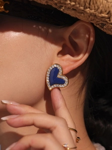 Close-up of heart-shaped earring with deep blue center and white crystal inlay