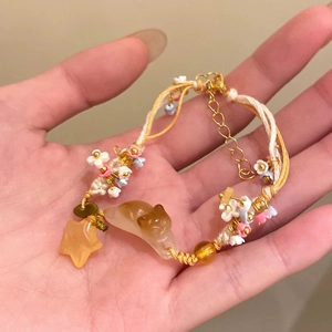 Gros plan d'un bracelet tissé main avec chaton en résine et breloques en forme d'étoile