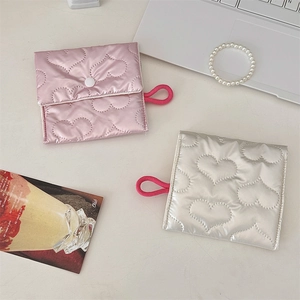 Quilted silver and pink heart pouches with snap closure on a minimalist desk