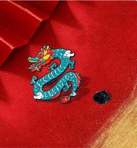 Macro shot of a teal and red enamel dragon brooch with golden outlines on red texture