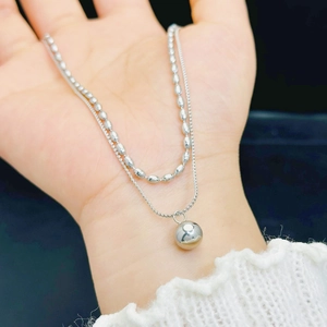 Double-layered titanium steel necklace with silver ball pendant held by hand