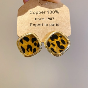 Close-up of square leopard print stud earrings with gold trim on jewelry display card