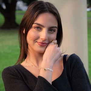 Golden heart bracelet with white stones and matching necklace worn by a model