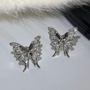 Elegant silver butterfly ear cuffs with sparkling zircon stones set on a plush white surface