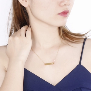 Detail of minimalist gold bar necklace with birthstone on model neck area
