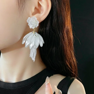 Close-up of elegant white floral tassel earrings with beads on a female model