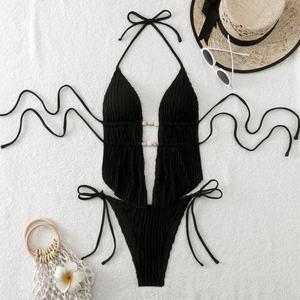 Flat lay of black halter monokini with marble beads and textured fabric details