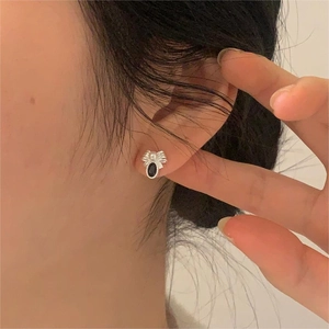 Gothic silver spider stud earring with black stone and white beads worn by a model