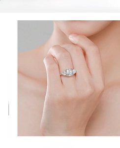 Close-up of a s925 silver cushion-cut ring with pear-shaped side stones on a finger