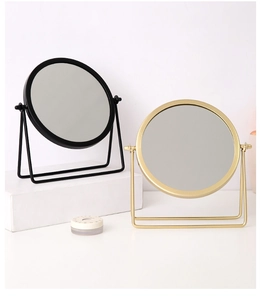 Detail view of modern black and gold iron desktop vanity mirrors on white base