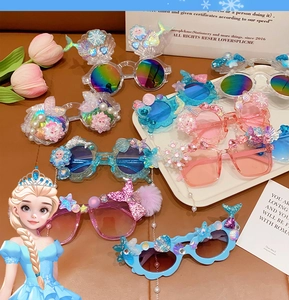 Flat lay of colorful girls' UV sunglasses with shell, pearl and snowflake decorations