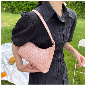 Pink crocodile pattern baguette bag detail with golden zipper on a picnic setup