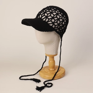 Detail of black crochet peak cap showing intricate hollow patterns and stylish tassels