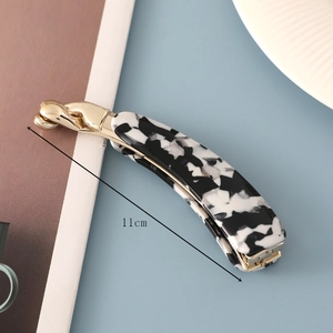 Detail view of 11cm spotted acetate banana hair clip on blue table with size mark