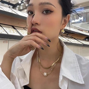 Double layered gold snake chain necklace with pearl pendant and geometric earrings