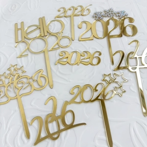Nahaufnahme goldener Acryl-Kuchenstecker für 2026 mit Sternen und Schneeflocken-Design