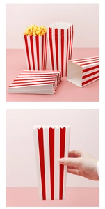 Classic red and white striped popcorn boxes made of paper in a stack and held by hand