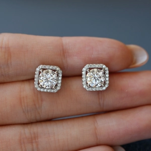 Square halo moissanite stud earrings in S925 silver held by hand with bright sparkle