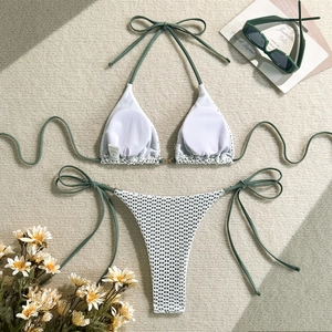 Detail of green crochet knit bikini with white hollow-out floral patterns and size label