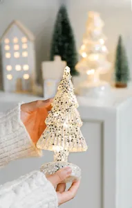 Close-up of glowing glass Christmas tree with silver stars and glitter base