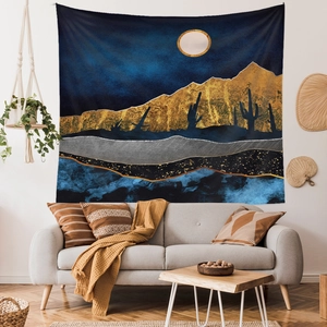 Modern abstract wall tapestry featuring moon, gold mountains, and cactus over a sofa