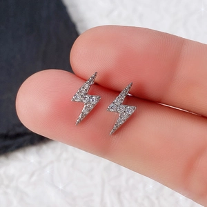 Macro shot of silver mini lightning bolt stud earrings with shimmering zircon stones