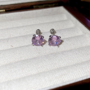 Macro shot of pink round zircon stud earrings with four-prong setting in a jewelry box