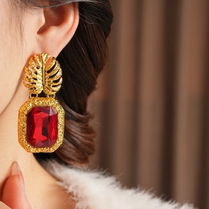 Détail de boucles d'oreilles vintage avec feuille dorée et grand cristal rouge rectangulaire