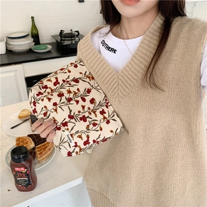 Détail d'une trousse de maquillage à fleurs en velours côtelé tenue à la main en cuisine