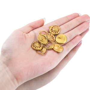 Retro gold stainless steel sun and moon pendants held by hand for DIY jewelry making